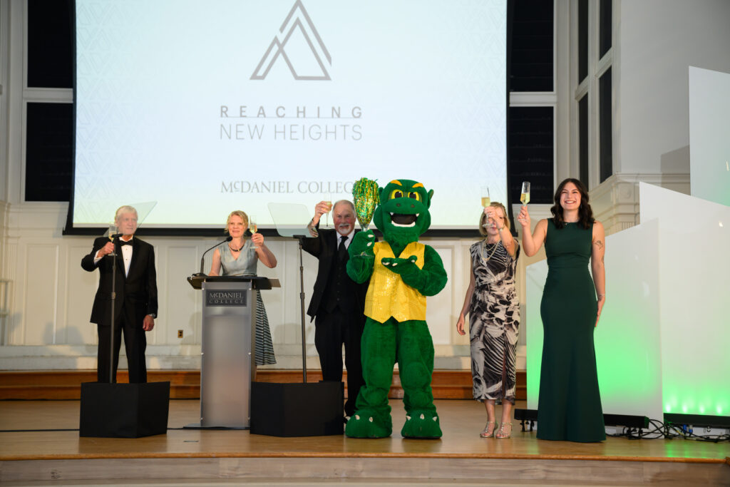 McDaniel Board of Trustees Chair Bruce Preston '75, McDaniel President Julia Jasken, student Nicki James, Debbie Dale Seidel '85, Ethan Seidel, and the Green Terror holding glasses of champagne.