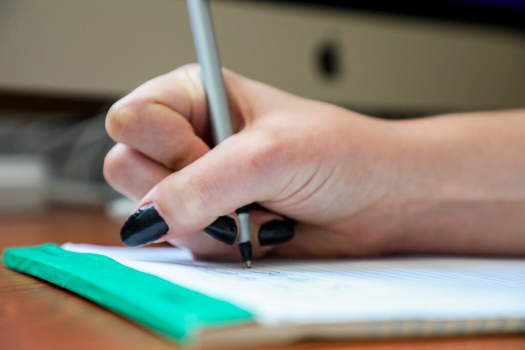 Close-up image of a hand holding a pen on paper.